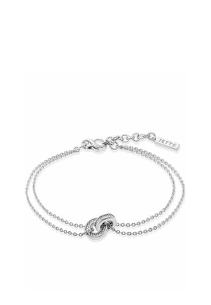Bracelet délicat en argent à double chaîne avec deux maillons circulaires entrelacés, dont l'un est incrusté de petites pierres claires, et un fermoir avec une étiquette "JETTE".