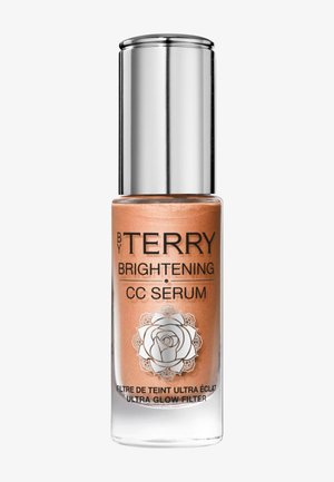 Flacon en verre transparent avec sérum CC illuminateur rose gold, bouchon argenté et étiquette "By Terry Brightening CC Serum Ultra Glow Filter".