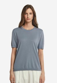 Ljusblå kortärmad topp i ett följsamt tyg. Har en ribbad halsringning och muddar. Avslappnad passform som slutar vid höfterna.