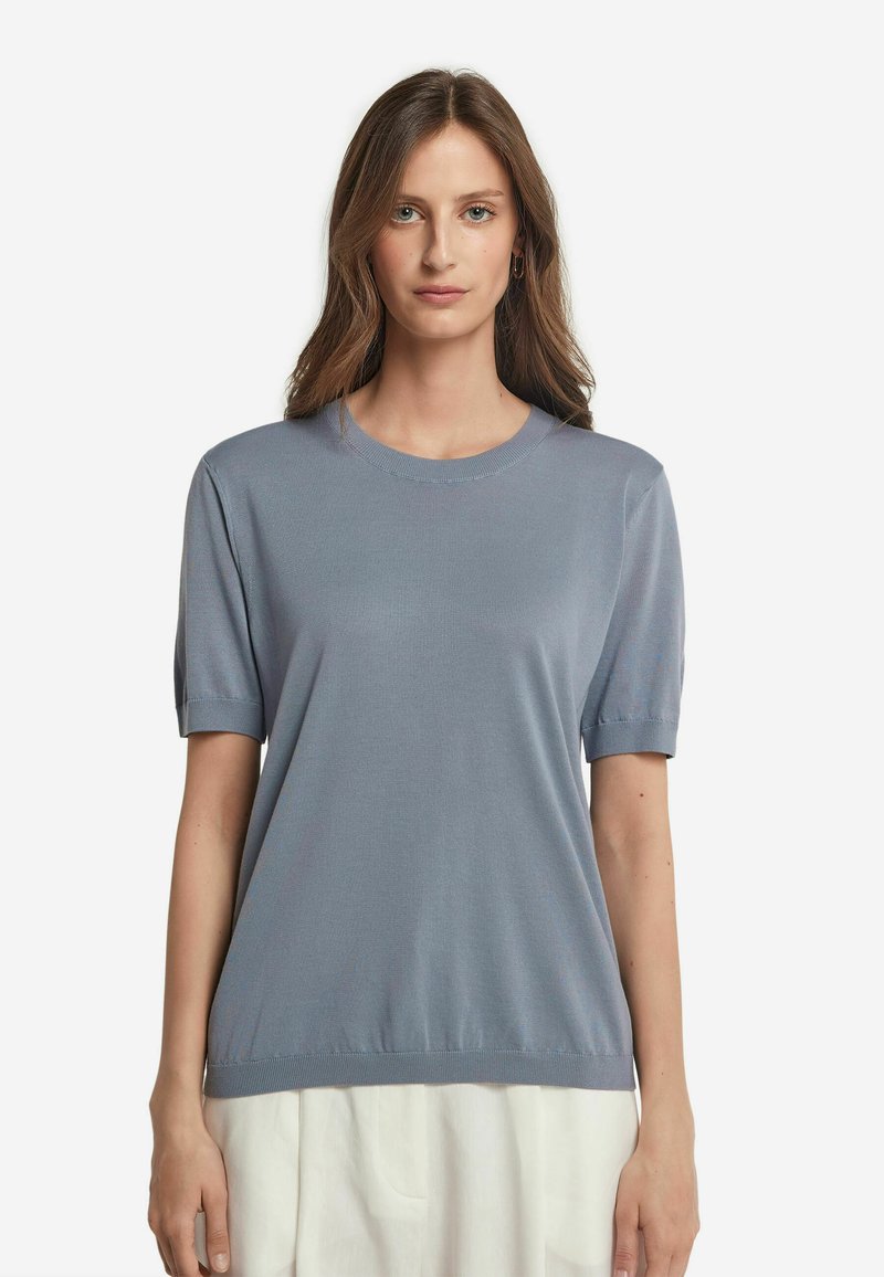 Ljusblå kortärmad topp i ett följsamt tyg. Har en ribbad halsringning och muddar. Avslappnad passform som slutar vid höfterna.