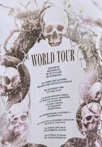 Koponyák és kígyók keretezik a "World Tour" szöveget, amely különböző európai városok helyszíneit és dátumait sorolja fel fehér háttéren.