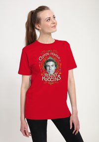 Červené bavlněné tričko s grafickým designem, na kterém je text „I AM A COTTON-HEADED NINNY MUGGINS“ a černobílá ilustrace obličeje.