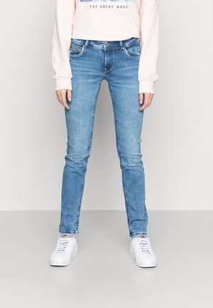 Lyseblå denimjeans med slim fit, fem lommer og let falmning. Båret med en lyserød sweatshirt og hvide sneakers.