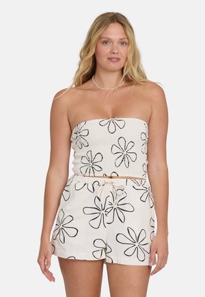 Górna część bez ramiączek z marszczonym białym materiałem, zdobiona czarnymi kwiatowymi wzorami; zestawiona z szortami na sznurku w tym samym kwiatowym wzorze.