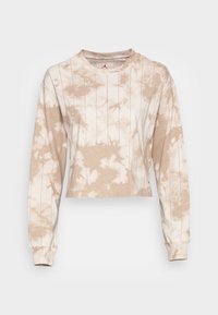 Beige och vit tie-dye kortärmad långärmad skjorta med tunna vertikala ränder och rundad hals, visad mot en enfärgad bakgrund.