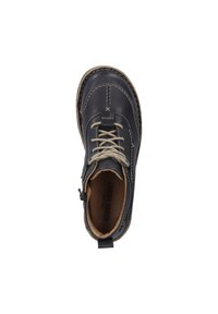 Bottine en cuir noir avec des coutures claires, bout rond, lacets beige et une languette à l'arrière. L'intérieur est doublé de beige.