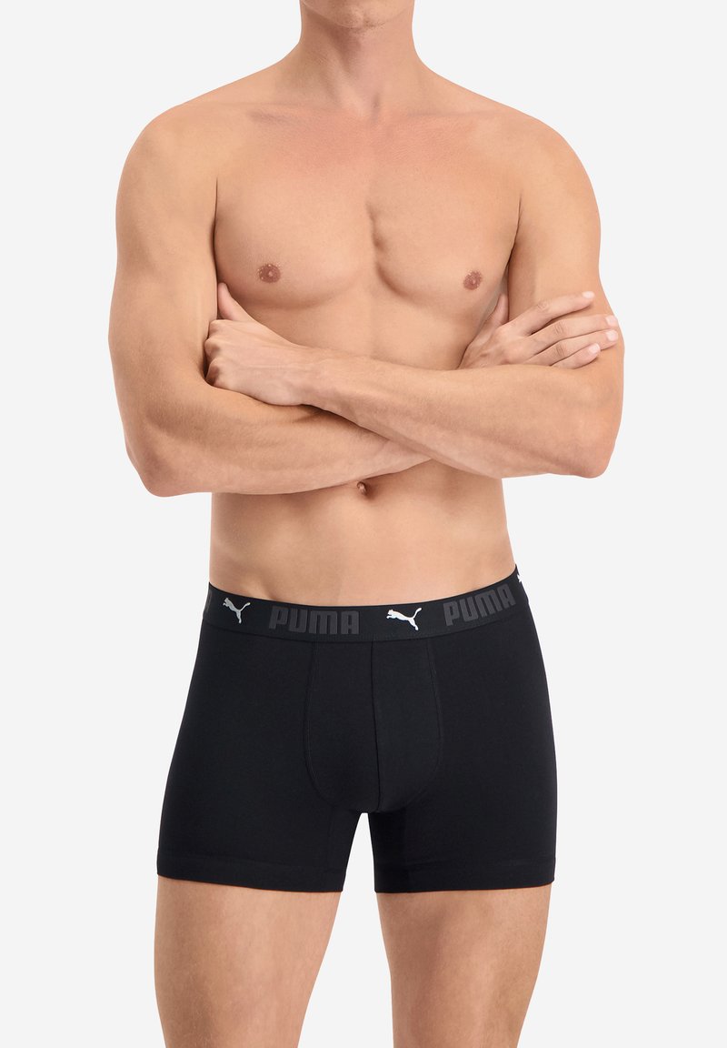 Schwarze Boxershorts mit enganliegendem Schnitt, aus weichem Stoff gefertigt. Der Bund zeigt das Puma-Logo in Grau auf schwarzem Hintergrund.