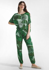 Grønt løvmønstret sæt lavet af let stof, med en løs top og tilspidsede bukser med elastik i talje og manchetter.