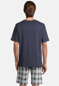 Mörkblå bomull T-shirt med korta ärmar, kombinerad med rutig shorts i vitt och mörkblått, med en avslappnad passform och mjuk textur.