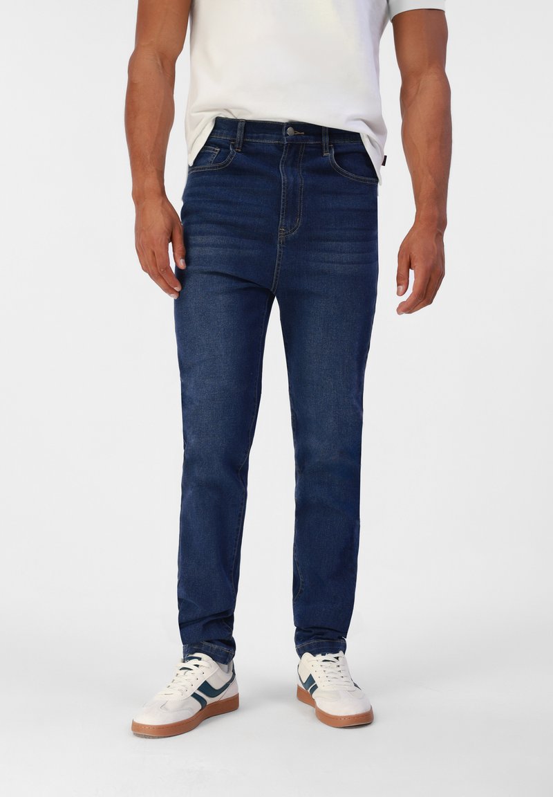 Temno modri kavbojki s slim fit krojem, z klasičnim pet žepnim dizajnom in rahlim bledenjem. Nosi se z belimi supergami in enobarvnim majico.