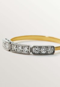 Pulsera de oro que presenta tres secciones de plata con gemas redondas y transparentes rodeadas de bordes texturizados y pequeñas cuentas.