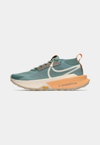 Turqoise hardloopschoen met een gestructureerde mesh bovenwerk, grijze accenten en een oranje hiel. Beschikt over een dikke ZoomX tussenzool en Vibram buitenzool.