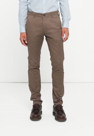 Brown cotton chinos with a slim fit, featuring a button closure, side pockets, and a smooth texture, paired with dark brown shoes.