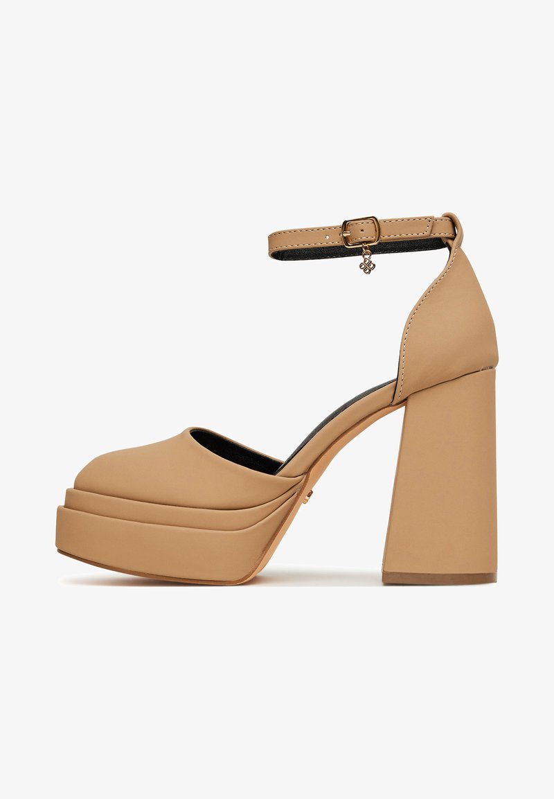 Beežid platvormkingad paksu kontsaga, pahkluu rihmaga, ümarate varvastega ja siledast sünteetilisest materjalist. Rihmal on dekoratiivne ripats.