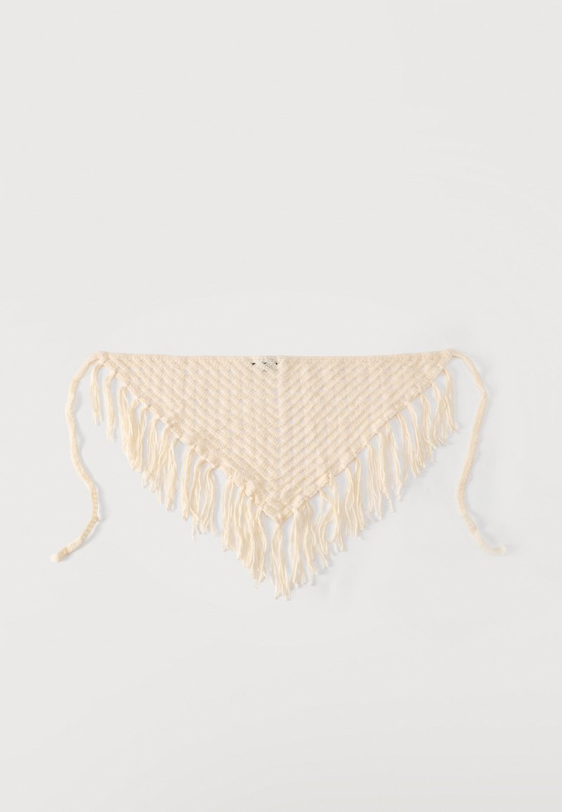 Écharpe tricotée triangulaire de couleur crème avec de longues franges sur les bords et deux liens pour l'attacher, sur fond blanc.
