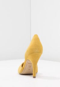 Scarpa con tacco alto in suede giallo con punta appuntita, caratterizzata da un tacco sottile e da un design traforato. Taglia indicata come 37 sulla soletta.