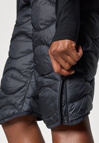 Calções em estilo puffa na cor preto mate, com textura acolchoada, fecho lateral e um corte relaxado, feitos de material leve e isolante.
