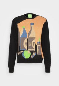 Svart tröja med orange frampanel som har en grafik av två flaskor märkta "HUF", ett grönt äpple, tärningar och en mugg med ett sugrör.