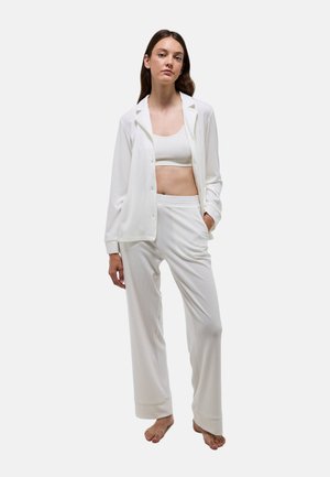 Ensemble de vêtements d'intérieur blanc composé d'une chemise à boutons avec poches et d'un pantalon à coupe décontractée, présentant une texture lisse et un design minimaliste.