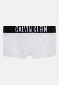 Biele boxerky vyrobené z bavlny, s čiernym elastickým pásom so sloganom "CALVIN KLEIN" vytlačeným na bielo. Hladká textúra a priliehavý dizajn.