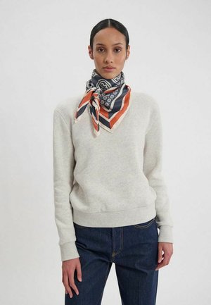 Sweatshirt en coton gris clair avec un col rond, assorti à une écharpe en soie à motifs dans des tons marine, orange et crème, nouée autour du cou.