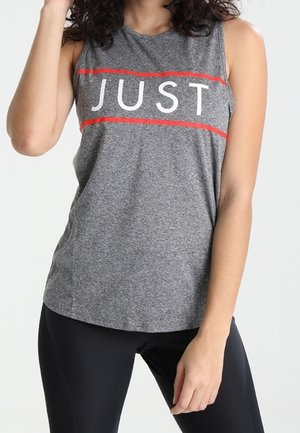 Person wearing a sleeveless gray top with the word "JUST" in white, bordered by two red lines, paired with black pants.