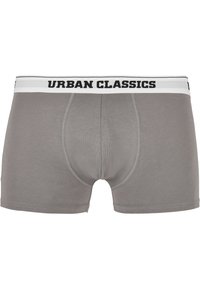 Grå boxertrosor i mjukt tyg med en svart och vit elastisk midja märkt "URBAN CLASSICS." Har en åtsittande passform och sydda detaljer.