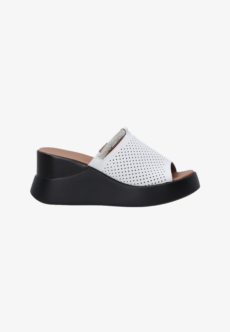 White perforated slide-on shoes with a rounded open toe and a black wedge heel. Features metallic accents and a smooth inner lining.