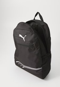 Zaino in tessuto nero con scomparto principale con zip, tasca frontale e tasca laterale in rete; presenta il logo Puma bianco e accenti bianchi curvi.