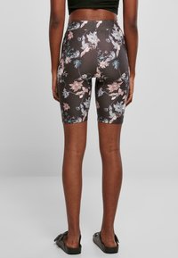 Kraťasy s vysokým pasem v tmavé látce s květinovým vzorem ve růžových a modrých akcenty, navržené pro pružnost a pohodlí.