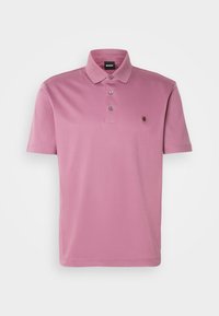 Polo rose à manches courtes pour homme avec trois boutons, col et petit logo poitrine sur fond blanc uni.