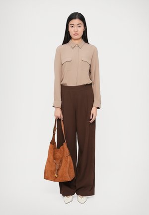 Bež dolg rokav bluza z dvema prsni žepoma, rjave široke hlače in rjava antilop torbica s trakom za zapiranje. Konice bele čevlje.