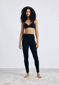 Black sports bra and leggings set, made of soft fabric. Leggings feature a high waist and form-fitting design. Plain, without patterns or accents.