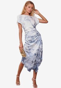 Abito a stampa floreale in azzurro chiaro e bianco, caratterizzato da un corpetto drappeggiato, vita cintrata e orlo fluente; abbinato a una pochette dorata.