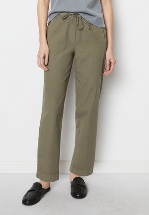 Pantaloni dritti color verde oliva con vita elasticizzata, realizzati in tessuto morbido. Indossati con mocassini neri, con dettagli cuciti.