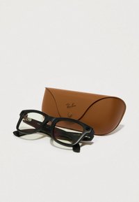 Lunettes Ray-Ban avec monture en plastique noir et verres teintés gris, à côté d'un étui en cuir beige avec un logo à l'avant.