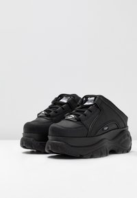 Svarta sneakers med en kraftig plattform, slät läderöverdel, rund tå, snörningsdesign och logotypdetalj på sidan.