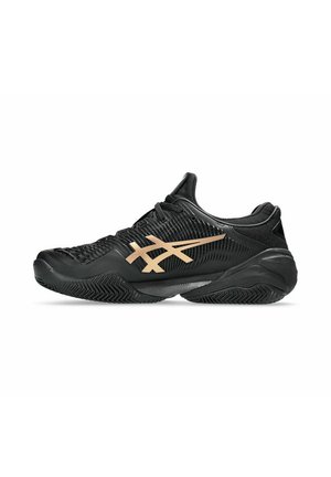 Baskets de sport noires avec une tige texturée, présentant un logo doré sur le côté et une semelle en caoutchouc durable avec un motif de semelle en zigzag.