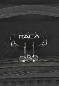 Cremallera negra de maleta con cerradura de combinación, con acabado metálico y el logo "ITACA" exhibido de forma destacada en el mecanismo de cierre.