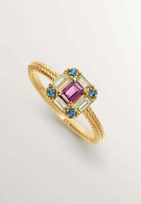 Anillo de oro con una banda trenzada, que presenta una piedra central de color púrpura rodeada de piedras de color verde claro y azul en una configuración cuadrada.