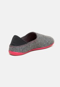 Chausson gris avec un accent en tissu noir au talon et une semelle en caoutchouc rose. Présente une forme arrondie et une texture douce.