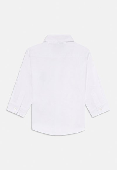 Chemise blanche avec col et manches trois-quarts, présentant une texture lisse et des accents de boutons aux poignets et au dos.