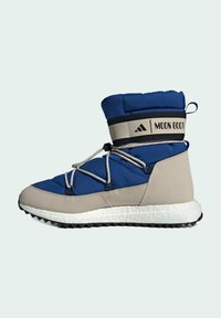 Blå och beige vadderad känga med texturerade material, justerbara snören, en vadderad krage och en gummisula med ett zigzag-mönster.