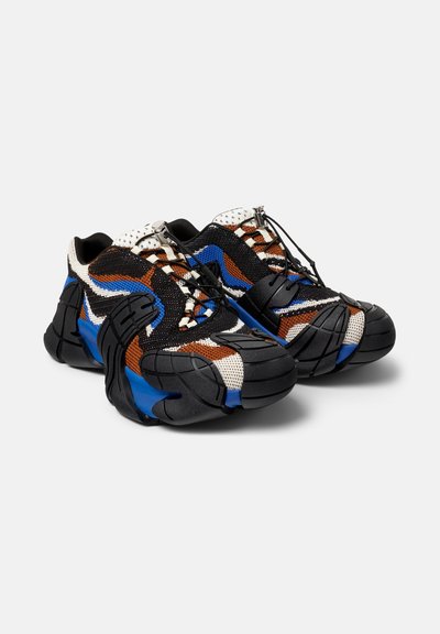 Bunte Sneakers mit einem gewebten Obermaterial in Schwarz, Blau, Braun und Weiß, dicker schwarzer Sohle und kontrastierenden Schnürsenkeln.