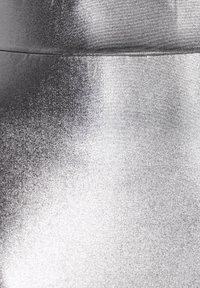 Tessuto metallico argento con una texture liscia e lucente. Presenta una leggera lucentezza e una superficie uniforme con cuciture minime visibili.