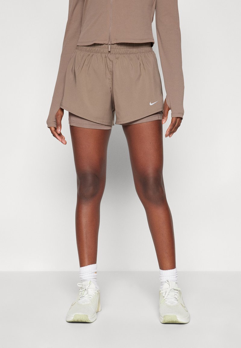 Hnědé sportovní šortky s elastickým pasem, se bílým logem Nike. Nosit s světlými teniskami a bílými krátkými ponožkami.
