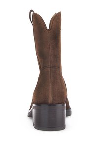 Bottes de cowboy en daim marron avec un col festonné, un bout pointu et un talon en bois empilé. Détails de couture notables le long des coutures.