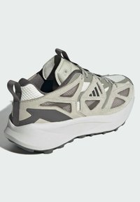 Light grey athletic shoe with textured mesh and suede accents. Features a thick white sole, padded collar, and contrasting dark grey details.