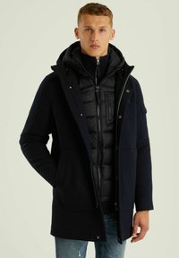 Jūrininkų striukė su užtrauktuku ir pūkinia vidine dalimi, su kapišonu, dviem priekinėm kišenėm ir tekstūruota apdaila. Yra užtrauktukas ir kontrastingas siuvinėjimas.