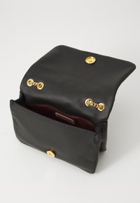 Black leather handbag with a fold-over flap, gold hardware, and a deep red interior. Features two gold accents and a magnetic closure.